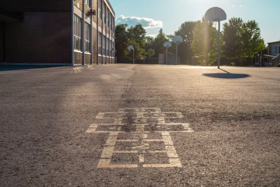 Hopscotch squares on concrete schoolyard with basketball hoop in background
